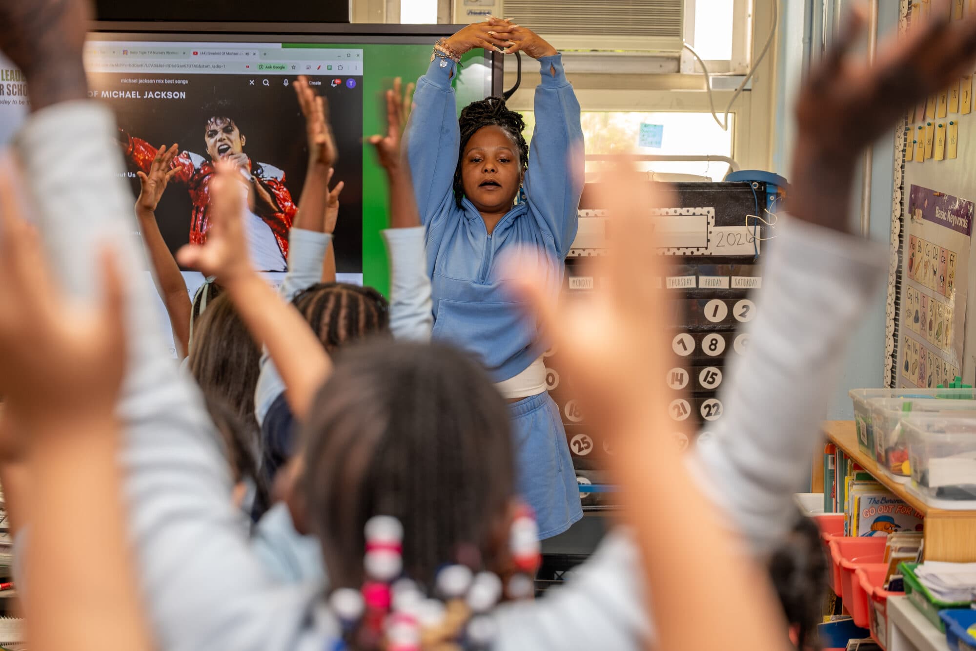 An FLI classroom full of students with hands raised, fully engaged.